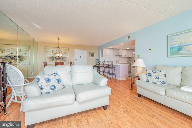 living room featuring a textured ceiling, sink, and light wood-type flooring