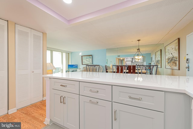 kitchen featuring white cabinets, light hardwood / wood-style flooring, and hanging light fixtures