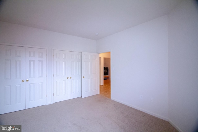 unfurnished bedroom with light colored carpet and multiple closets