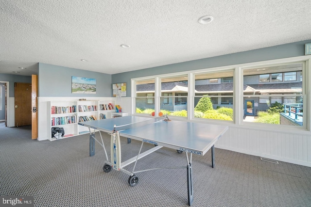 recreation room featuring plenty of natural light, a textured ceiling, and carpet floors