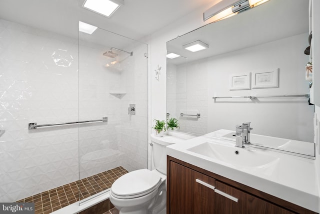 bathroom with toilet, vanity, tile patterned flooring, and tiled shower