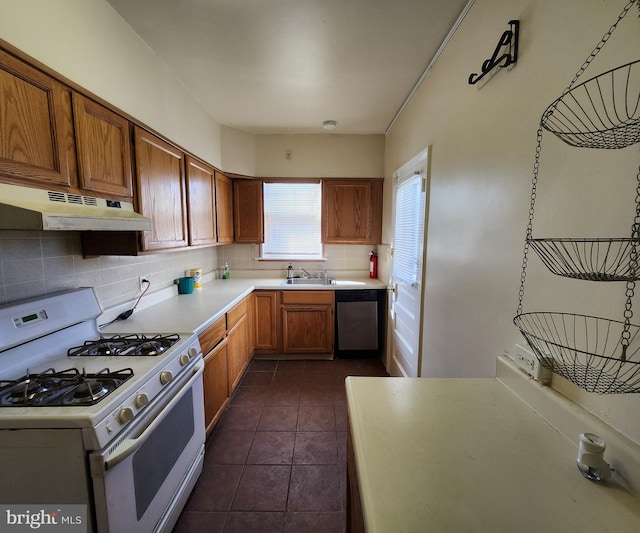 kitchen with tasteful backsplash, white gas range, dark tile patterned flooring, sink, and stainless steel dishwasher