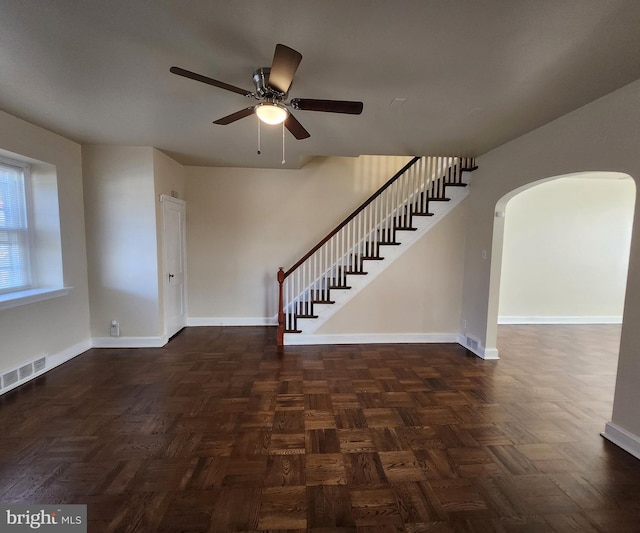 interior space with dark parquet flooring and ceiling fan