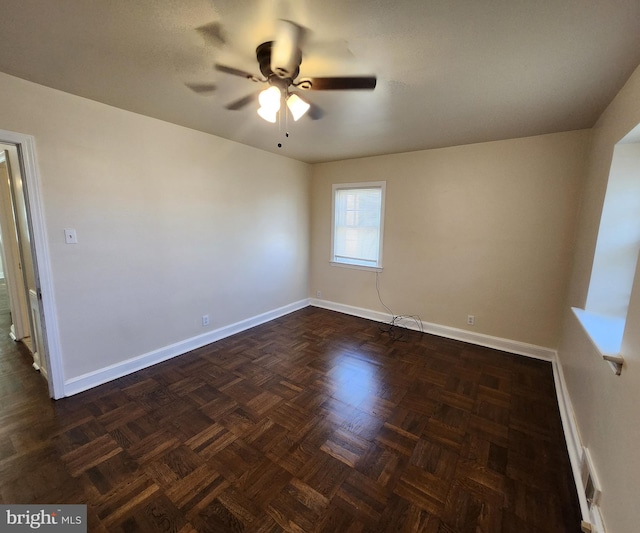 spare room with dark parquet flooring and ceiling fan