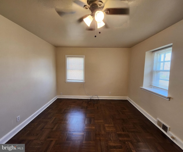 spare room featuring dark parquet flooring and ceiling fan