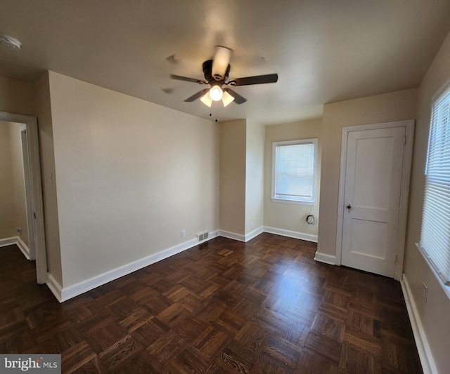 unfurnished room with ceiling fan and dark parquet flooring