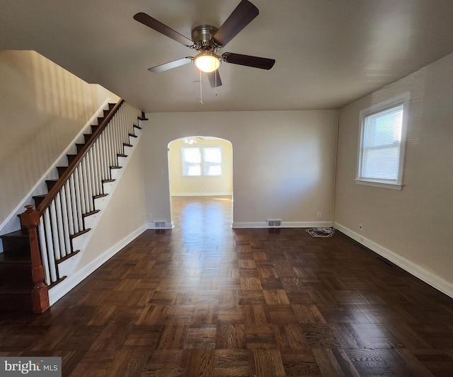 empty room with dark parquet floors, ceiling fan, and plenty of natural light