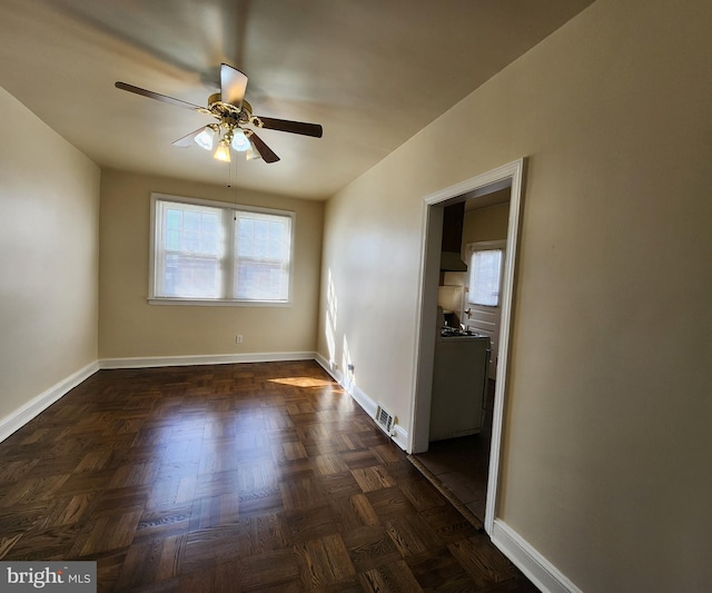 empty room with dark parquet floors and ceiling fan