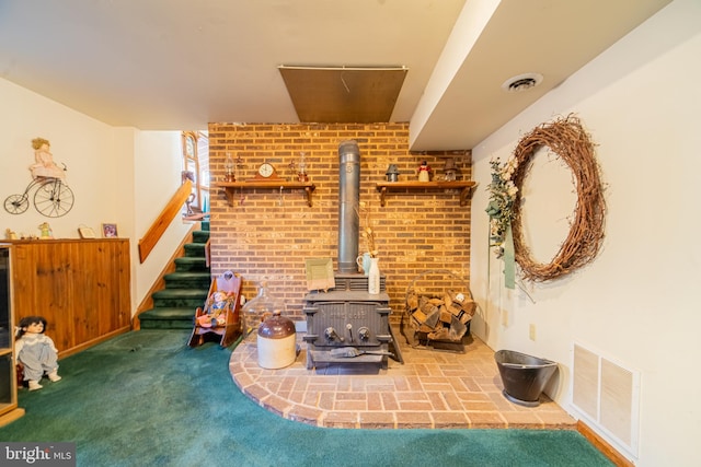 unfurnished living room featuring a wood stove, carpet floors, and brick wall