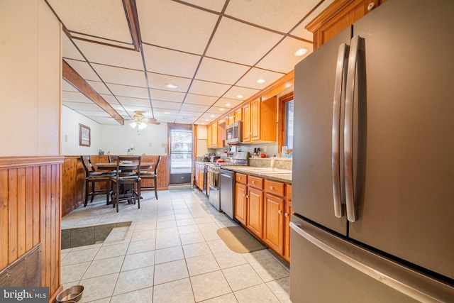 kitchen featuring a drop ceiling, sink, ceiling fan, light tile patterned flooring, and appliances with stainless steel finishes