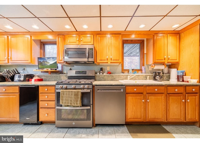 kitchen featuring sink, appliances with stainless steel finishes, a drop ceiling, and light tile patterned floors