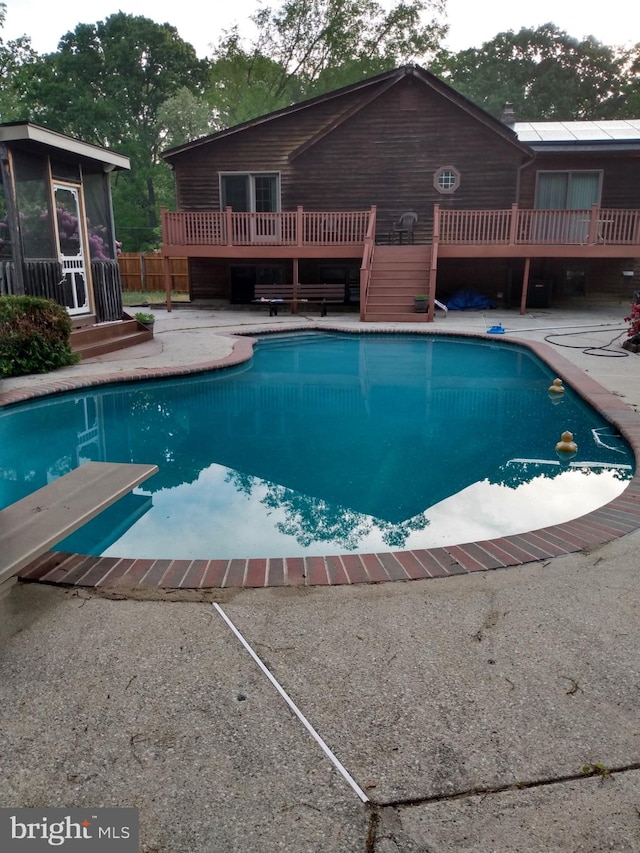 view of swimming pool with a diving board, a wooden deck, and a patio area