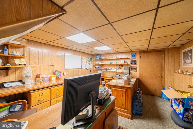 carpeted office space featuring wood walls and a drop ceiling