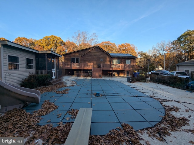 view of swimming pool featuring a water slide, a diving board, a deck, and a patio area