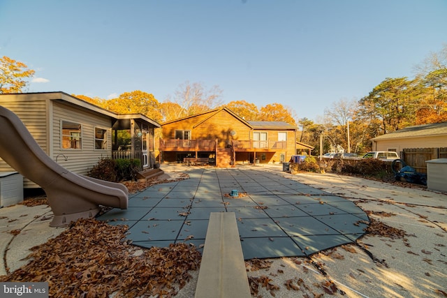 view of pool featuring a diving board, a wooden deck, a patio, and a water slide