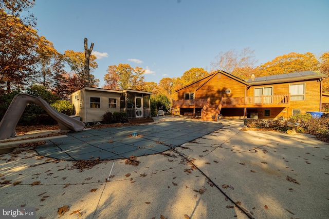 back of house with solar panels and a swimming pool side deck