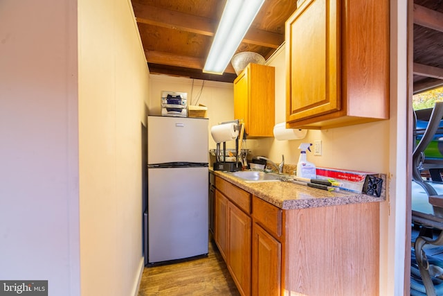 kitchen featuring light hardwood / wood-style floors, sink, white fridge, and beam ceiling