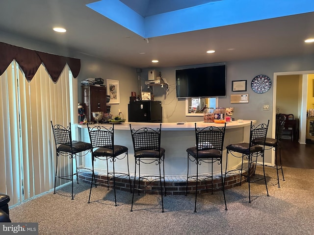 bar featuring carpet flooring and black refrigerator