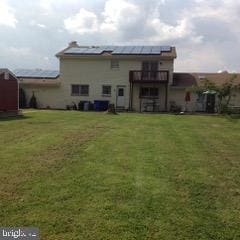 back of house with a yard and a balcony