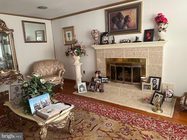 living room with hardwood / wood-style floors, ornamental molding, and a tiled fireplace