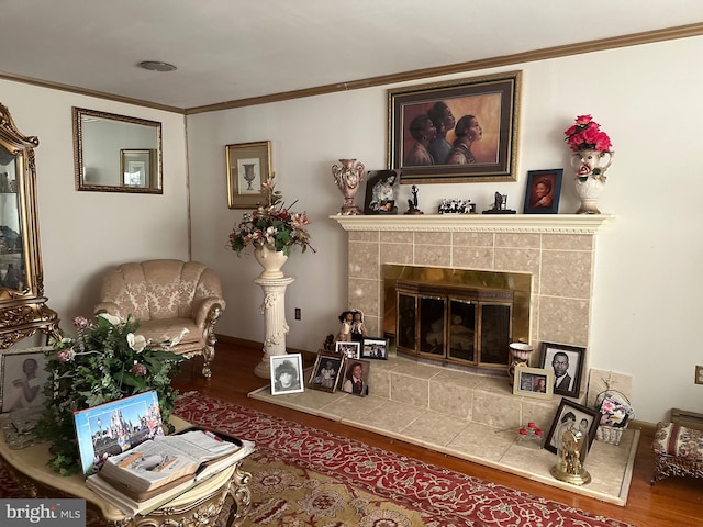 living area with hardwood / wood-style floors, ornamental molding, and a tiled fireplace