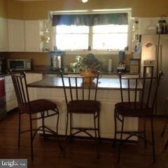 kitchen featuring white cabinets, a kitchen breakfast bar, and dark hardwood / wood-style floors