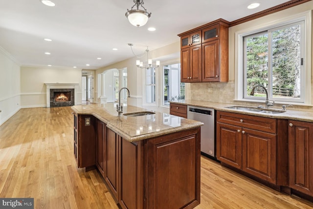 kitchen with dishwasher, sink, hanging light fixtures, light hardwood / wood-style flooring, and a center island with sink