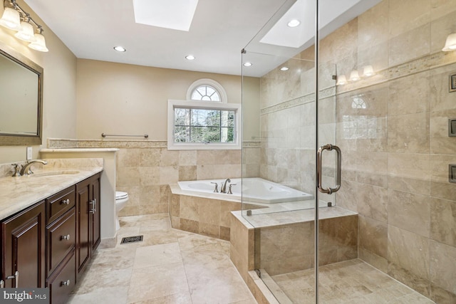 full bathroom with vanity, separate shower and tub, toilet, and a skylight