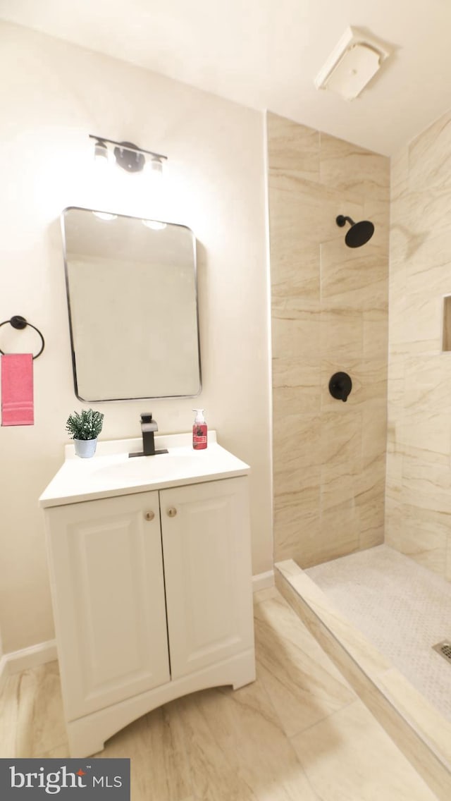 bathroom featuring tiled shower and vanity