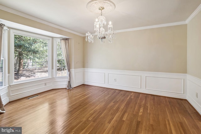 spare room with a chandelier, hardwood / wood-style flooring, and ornamental molding