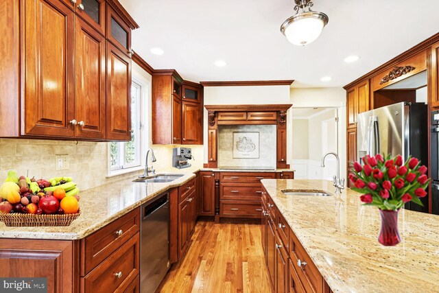 kitchen featuring light stone counters, sink, appliances with stainless steel finishes, and light hardwood / wood-style flooring