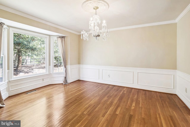 unfurnished room with a chandelier, wood-type flooring, and ornamental molding