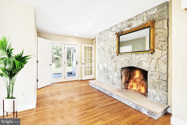 interior space featuring wood-type flooring, a stone fireplace, and french doors