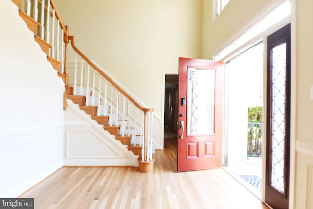 foyer with light hardwood / wood-style floors, a high ceiling, and a wealth of natural light