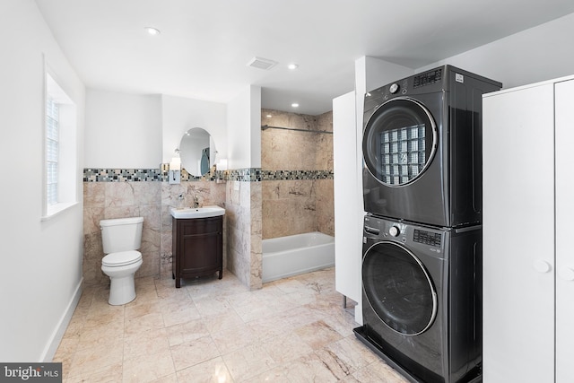 washroom with tile walls, sink, and stacked washer and dryer