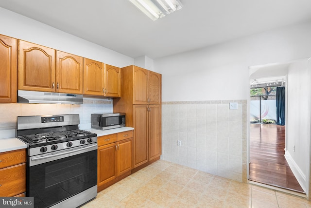 kitchen with tile walls, appliances with stainless steel finishes, and light wood-type flooring