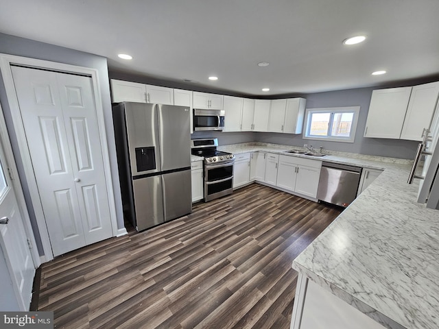 kitchen with sink, appliances with stainless steel finishes, dark wood-type flooring, and white cabinetry