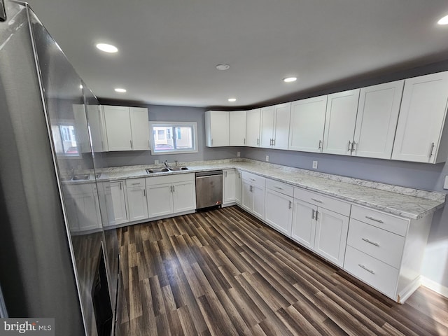 kitchen with white cabinets, light stone counters, appliances with stainless steel finishes, dark hardwood / wood-style floors, and sink