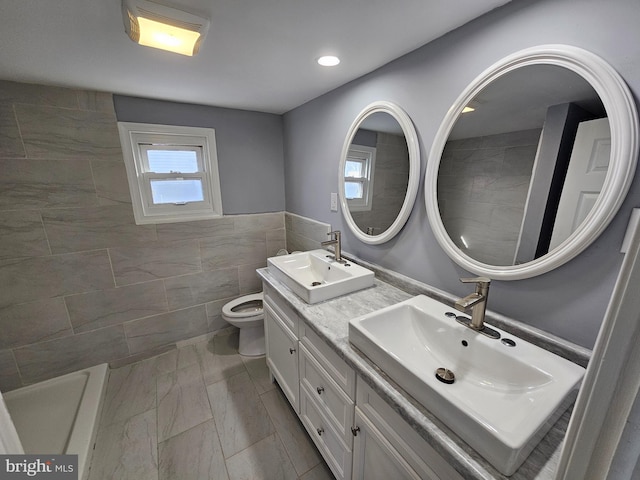 bathroom featuring vanity, toilet, and tile walls