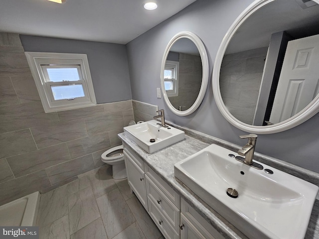 bathroom featuring vanity, toilet, and tile walls