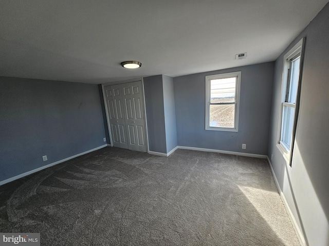 unfurnished bedroom featuring dark carpet and a closet