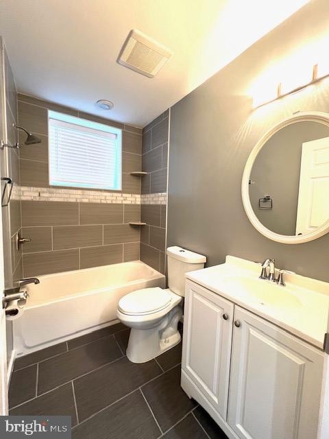 full bathroom with tile patterned flooring, tiled shower / bath, toilet, and vanity