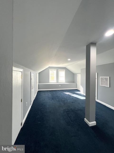 bonus room with vaulted ceiling and dark carpet