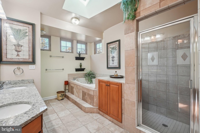 bathroom featuring a skylight, independent shower and bath, vanity, and tile patterned flooring