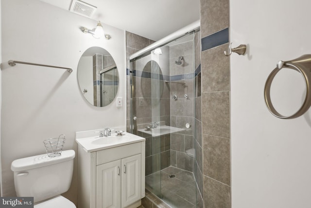 bathroom featuring vanity, toilet, and a shower with shower door