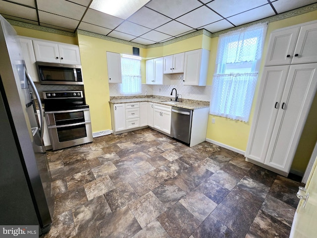 kitchen featuring stainless steel appliances, white cabinets, sink, and a paneled ceiling