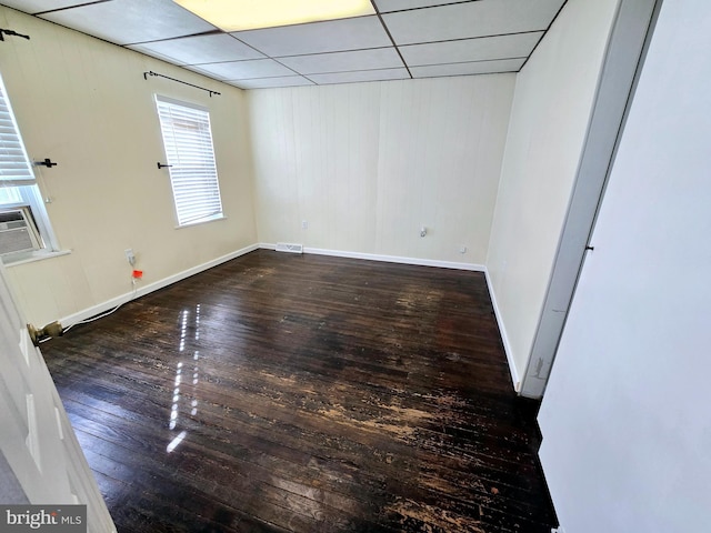 empty room featuring a paneled ceiling and dark hardwood / wood-style flooring