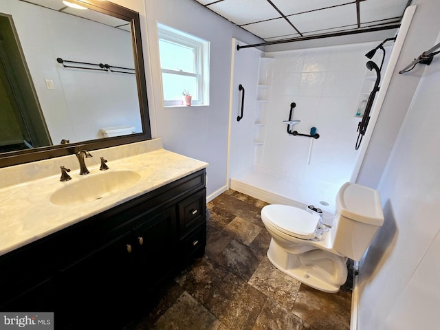 bathroom with a shower, vanity, toilet, and a paneled ceiling