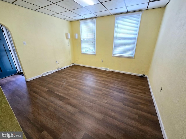 unfurnished room featuring a healthy amount of sunlight, dark hardwood / wood-style flooring, and a drop ceiling