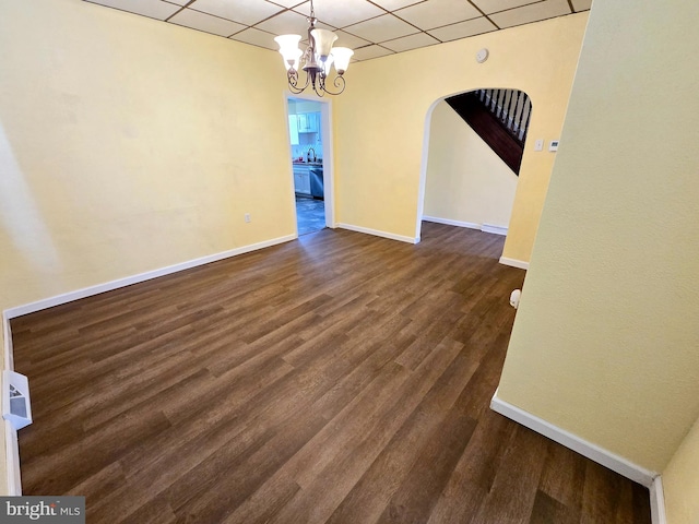 unfurnished dining area featuring a chandelier, a paneled ceiling, and dark hardwood / wood-style flooring